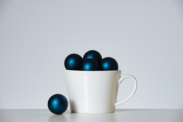 Christmas balls in white cup on white background