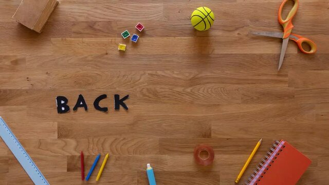 Back to class stop motion with school suplies appearing on a wooden desk and the sentence "Back to school"