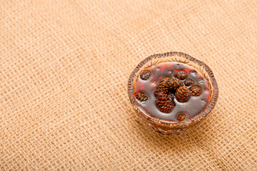 Young pine cones jam. Useful and tasty dessert. Traditional Siberian dessert - young pine cones jam. Glass ramekin of jam made from pine cones on a white background.