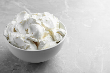 Bowl of tasty cream cheese on light grey marble table, space for text