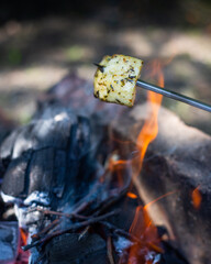 Halloumi cheese is fried over a bonfire, with a beautiful flame.