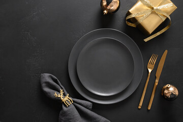 Christmas and New Year luxury table setting for dinner with black plates, gold gift and decorations...