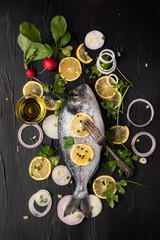 Raw fish on black background and vegetables, top view photo