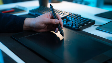 Close Up Shot of an Animator Holding a Pen and Drawing on the Pad With a Keyboard in Front of Him.