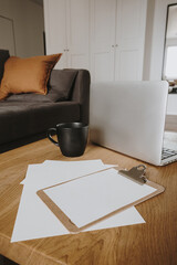 Blank paper sheet tablet pad with mockup copy space, mug, laptop computer on wooden table. Home office desk workspace