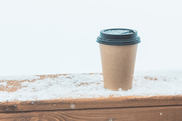 One disposable coffee cup on the snow on a wooden board. - Powered by Adobe