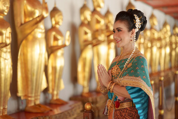 Portrait Asian women smiling and wearing Thai national costumes are inside temples to worship...
