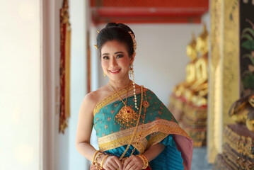 Portrait Asian women smiling and wearing Thai national costumes are inside temples to worship...