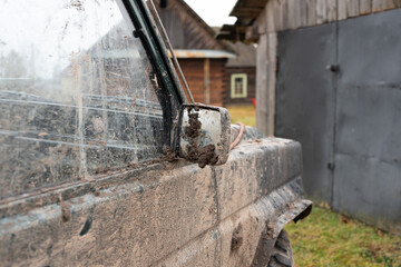 Car side mirror in the mud. Dirty jeep in the village.