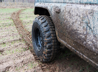 Fototapeta na wymiar Dirty jeep wheel close up. Wheel mark on the ground.