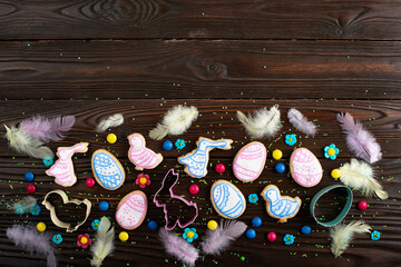Cookie cutters feathers and Easter frosted cookies in shape of egg, chicken and rabbit on dark...