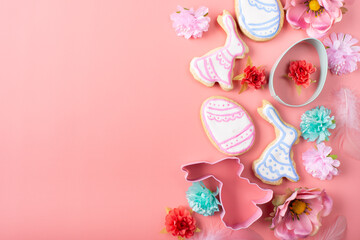 Easter cookies candies sugar sprinkles and cutters on pink background. Space for text