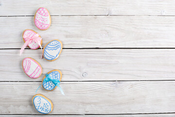 Homemade Easter cookies in shape of eggs on white wooden kitchen table flat lay view. Space for text