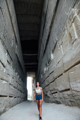 Obraz na płótnie Canvas beautiful brunette woman walking in a stone tunnel