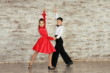 Beautifully dressed couple of kids dancing together in studio