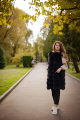 photo session of the girl in the park in autumn. back light. girl stands near a yellow tree on the sidewalk. full-length portrait of a girl with background.