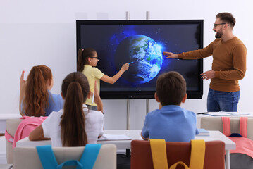 Teacher and pupil using interactive board in classroom during lesson