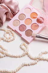 Makeup brush, pearl necklace and shadow palette. Makeup cosmetics tools background and beauty cosmetics. Vertical