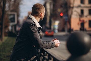 a short-haired man is thoughtful and stands near the road. looks into the distance. without a face