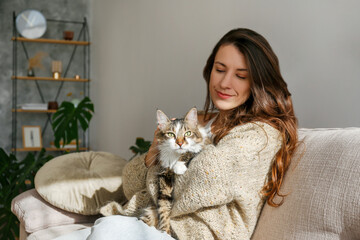 Portrait of young woman holding cute siberian cat with green eyes. Female hugging her cute long hair kitty. Background, copy space, close up. Adorable domestic pet concept. - Powered by Adobe