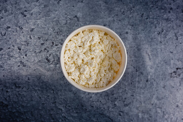 White bowl with cottage cheese on gray background