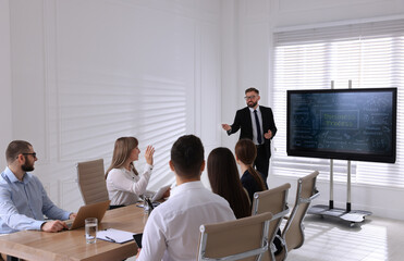 Business trainer near interactive board in meeting room during presentation