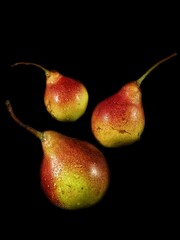Yellow pears with a red side on a black background with selective focus