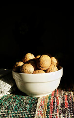 Inshell walnuts in white bowl. Rustic style kitchen detail.