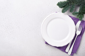 Christmas table setting white color with silverware, napkin trendy color very peri in 2022 Year, Christmas balls, stars, champagne, glasses on white background for xmas greetings. Mock up.