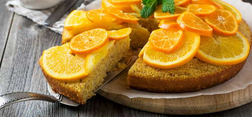 Orange and mandarin cake with polenta, upside down on the old wooden background. Selective focus.