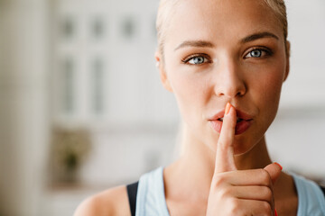 Fototapeta premium Blonde young woman showing silence gesture during yoga practice