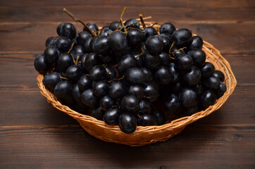 dark grapes in a basket on a wooden background