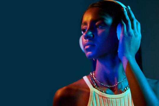 Black Brazilian woman listening to music under fluorescent light