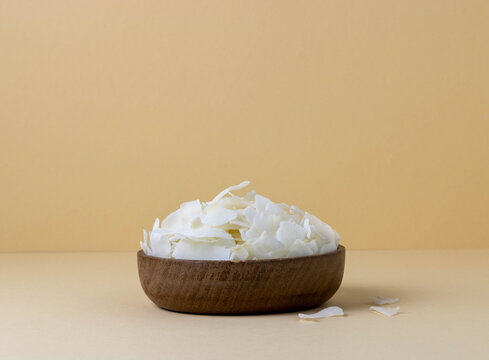 Fruit crispy coconut chips in wooden bowl on beige background with copy space