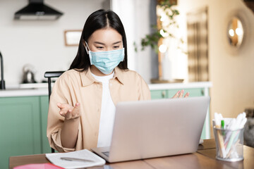 Fototapeta na wymiar Young asian woman, student talking on video conference, attend lecture in medical face mask, online studying while on quarantine