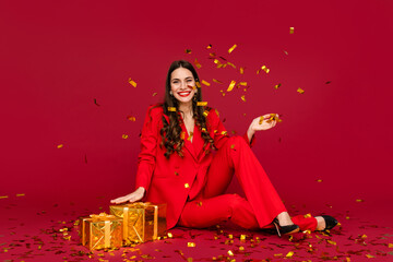 attractive woman celebrating Christmas on red background in confetti