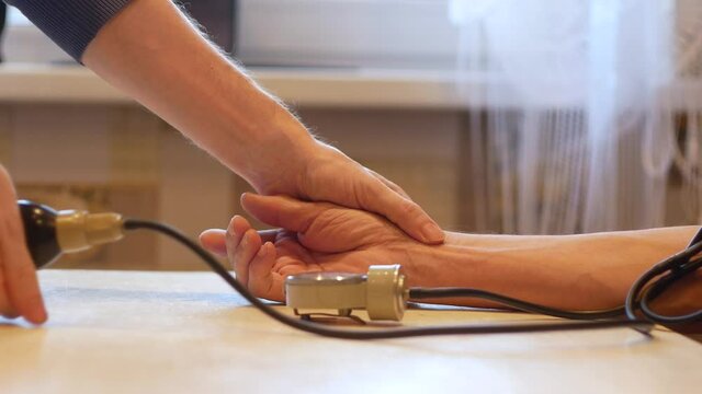 Measurement of blood pressure in the elderly is a topic. Adult Son measures his pulse and blood pressure with a tonometer for an elderly father while at home. Caring for the health of elderly relative