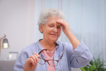 Senior woman with headache in room at home