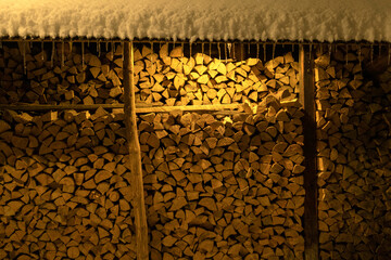 Wood storage stockpile in row. Firewood stacked in winter. Chopped stock of firewood under snow. Pile of firewood in winter. Pile of firewood covered in snow.
