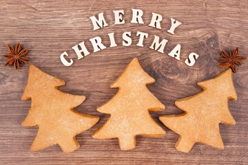 Fresh baked gingerbreads in shape of christmas tree and inscription Merry Christmas
