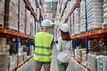 Back view of woman and man in warehouse aisle