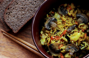 A dish for vegans. Rice with mushrooms and vegetables: champignons, carrots, onions, garlic, black pepper, red pepper, turmeric, olive oil, cumin