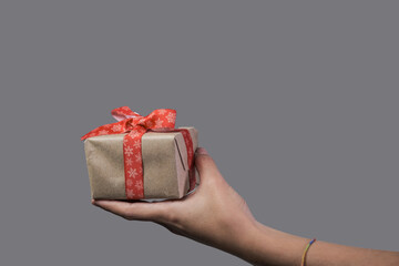 close up photo of mini gift pack with red ribbon standing in woman's hand in front of her
