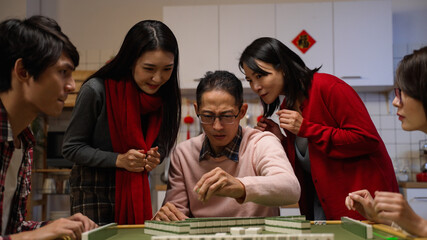 slow motion happy father drawing tile in beckoning other mahjong players formoney while his wife and daughter celebrating for his win with clenched fist. word translation: luck