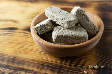 Sweet sunflower halva in a wooden bowl on a wooden table. Rustic style. Traditional natural sweets. Vegan food. Copy space.