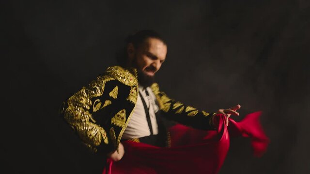 Male dancer or toreador imitating moves of matador bullfighter on black smoky background . Man bullfighter dressed in bullfighting costume . Shot on ARRI Alexa cinema camera in Slow Motion
