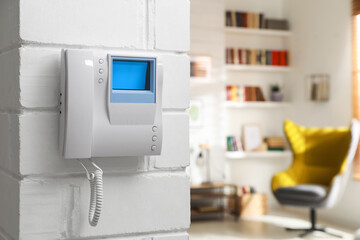 Modern intercom with camera installed on white wall indoors