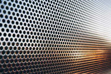 perforated shiny metal. outside. glare of the sun