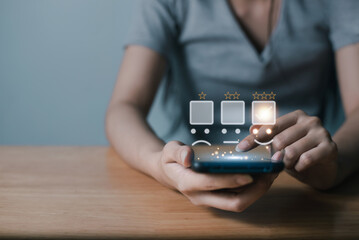 Businesswoman pressing face emoticon on virtual touch screen at smartphone .Customer service evaluation concept.