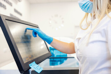 New technologies in a lab. A nurse standing next to a machine for blood analyzing and programing it.